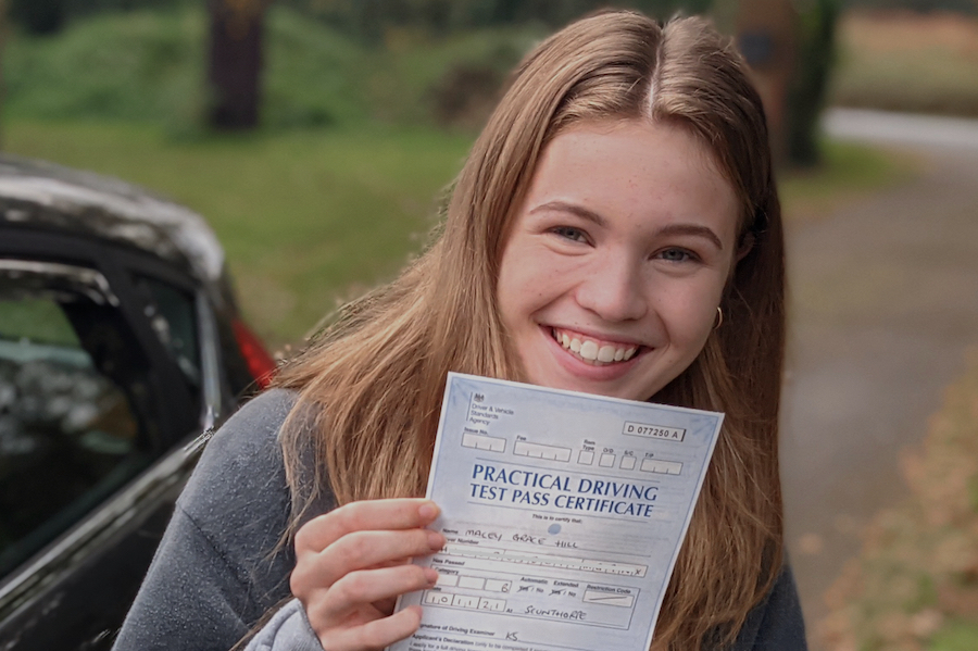 Young lady holding her driving test pass certificate
